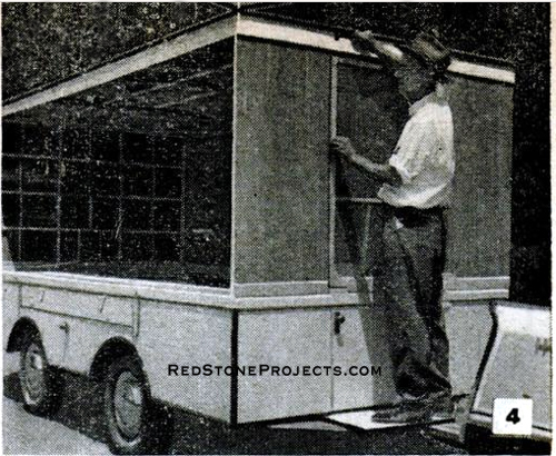 A man raising the front side panel and folding door of a folding hardside trailer.